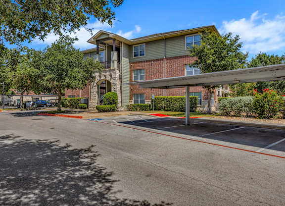 A parking lot in front of a multi-story apartment building.