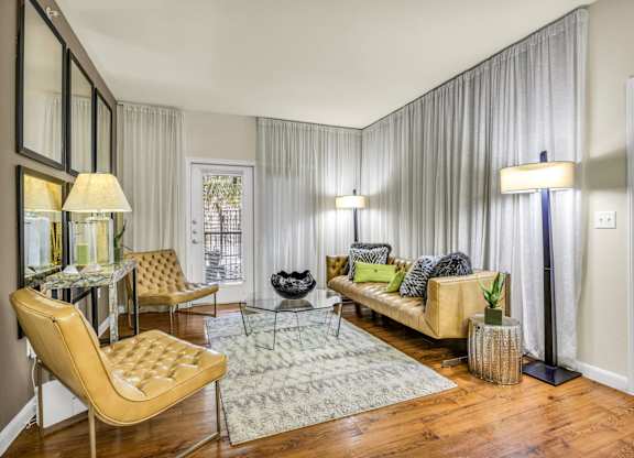 A living room with a yellow chair and a glass table.