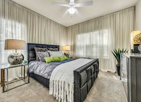 A bedroom with a large bed and a ceiling fan.