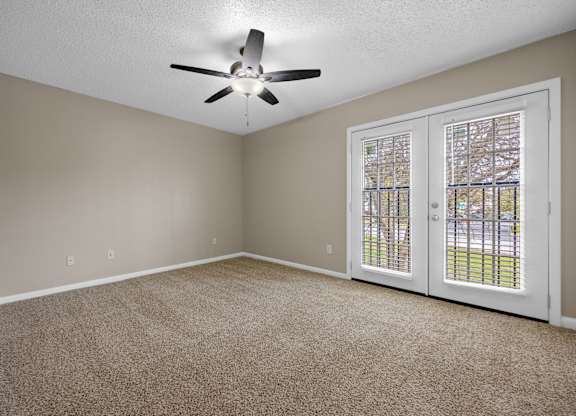 A room with a ceiling fan and carpeted floor.