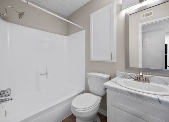 A white bathroom with a toilet, sink, and bathtub.