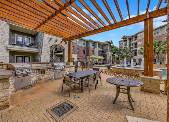 A patio with a table and chairs under a wooden pergola.