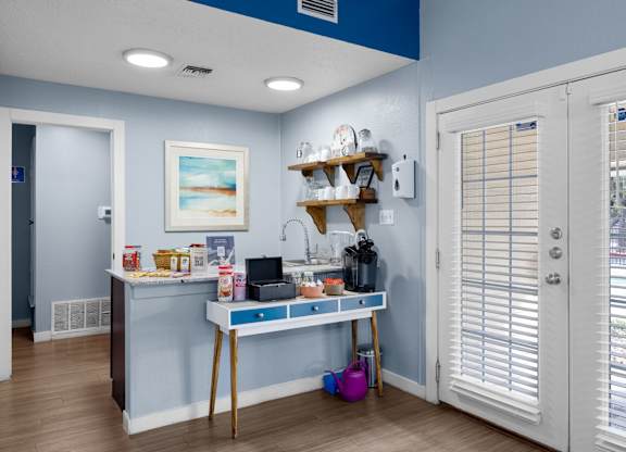 A kitchen area with a table and a shelf with various items on it.