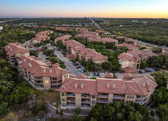 A sunset view of a large residential complex with multiple buildings and parking lots. at Bridge at Heritage Woods, Austin, Texas