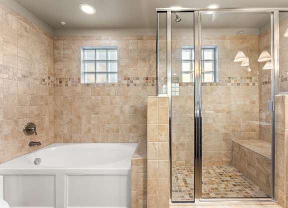 A bathroom with a white tub and a walk-in shower. at Bridge at Heritage Woods, Austin, 78753