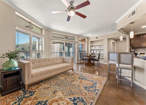 A living room with a beige couch, a rug, and a ceiling fan. at Bridge at Heritage Woods, Austin, 78753