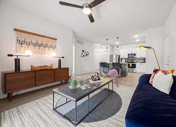 A modern living room with a dark blue couch and a glass coffee table. at Bridge at Tech Crossing, Austin, TX