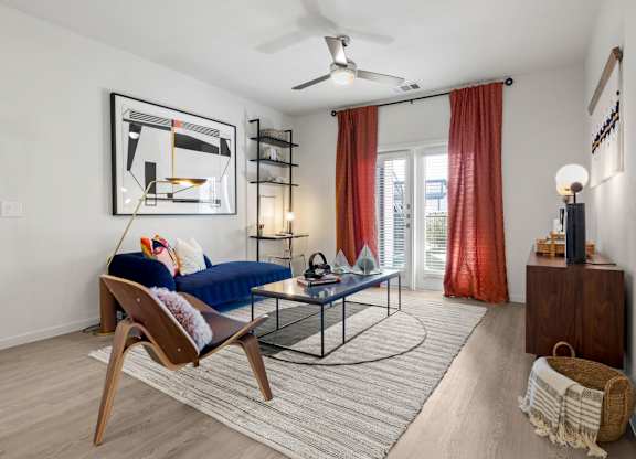 A living room with a blue sofa and a wooden chair. at Bridge at Tech Crossing, Austin, Texas