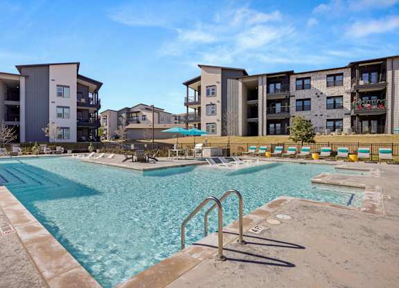 A swimming pool in front of apartment buildings. at Bridge at Tech Crossing, Austin, Texas