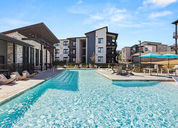 A large swimming pool in front of apartment buildings. at Bridge at Tech Crossing, Austin, TX, 78753