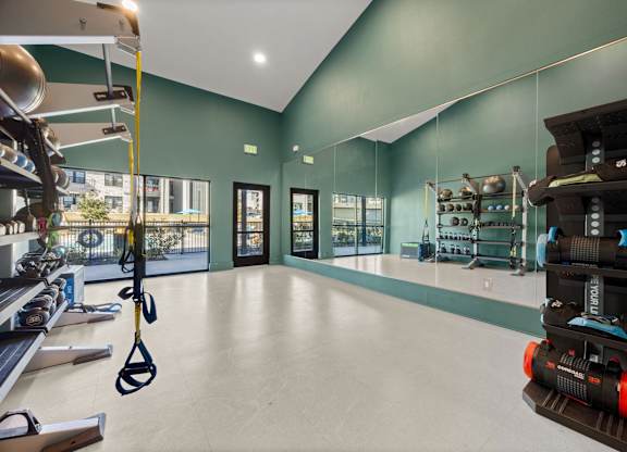 A gym with a green wall and a black and orange exercise bike. at Bridge at Tech Crossing, Austin