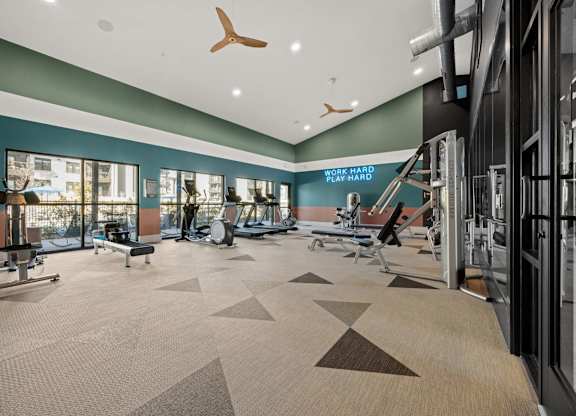 A gym with a variety of equipment including a treadmill, weights, and a bench press. at Bridge at Tech Crossing, Austin, TX