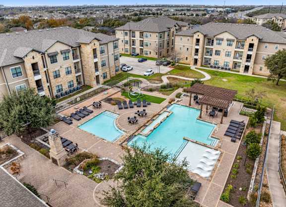 A large swimming pool surrounded by a grassy area and apartment buildings. at The Royce at 8100, Austin, TX, 78729