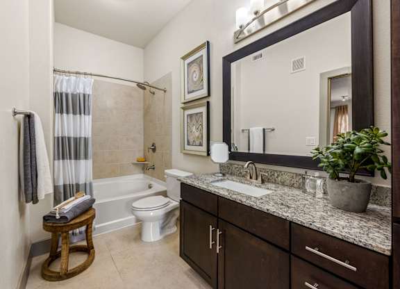 A bathroom with a white toilet, a sink, and a shower. at The Royce at 8100, Texas