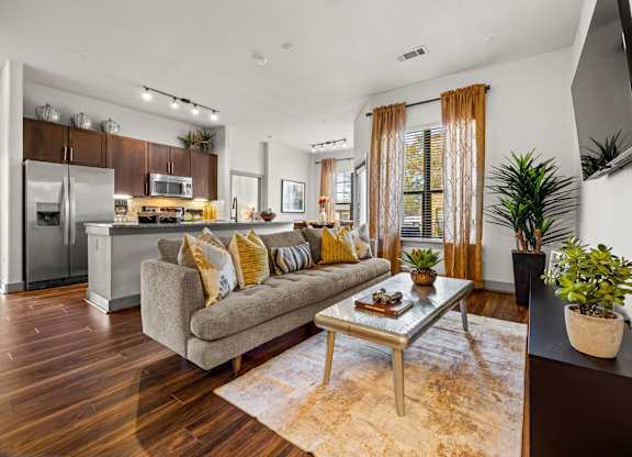 A modern living room with a grey couch and a wooden floor. at The Royce at 8100, Austin