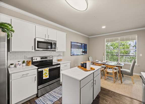 A kitchen with white cabinets and a black stove top oven. at Bridge at Canyon Creek, Austin, Texas