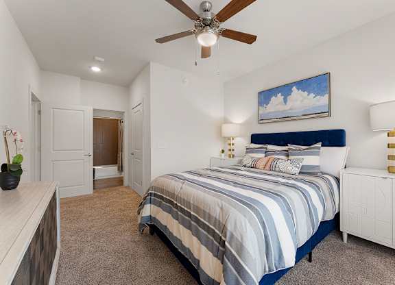 A bedroom with a bed, nightstand, and a ceiling fan.