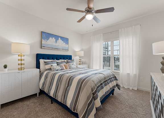 A bedroom with a bed, nightstands, and a ceiling fan.