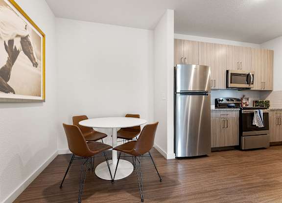 A kitchen with a table and chairs and a painting on the wall.