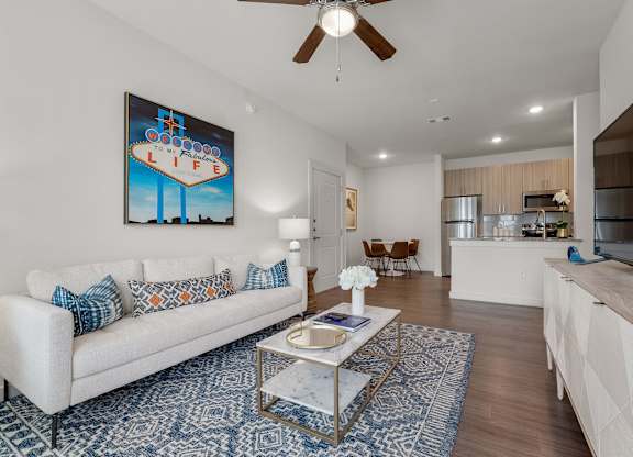 A living room with a white couch and a painting on the wall.