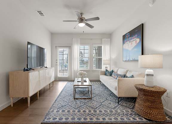 A living room with a white couch, a wooden cabinet, a flat screen TV, a coffee table, and a rug.