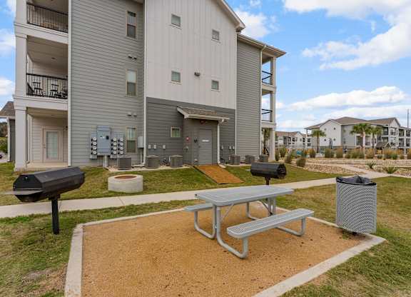 A grey apartment building with a picnic table in front.
