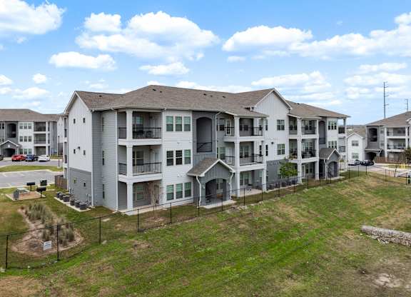 A large apartment complex with multiple buildings and a parking lot in front.