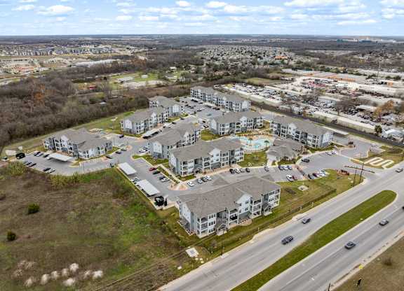 A large apartment complex is surrounded by a parking lot and a road.