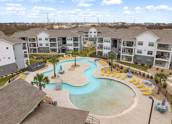 A large swimming pool surrounded by yellow sun loungers and palm trees.