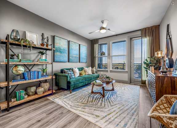 A living room with a green couch and a wooden coffee table. at Bridge at Henley, Austin, TX, 78741