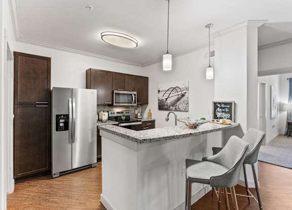 A kitchen with a white island and two chairs. at Bridge at Indigo, Austin, 78717