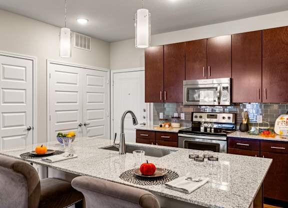A kitchen with a table and chairs in the foreground and a microwave above the stove. at Bridge at Southpark Meadows, Austin, TX, 78748