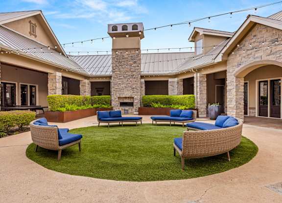 A patio with a stone fireplace and blue cushioned chairs. at The James on South First, Texas