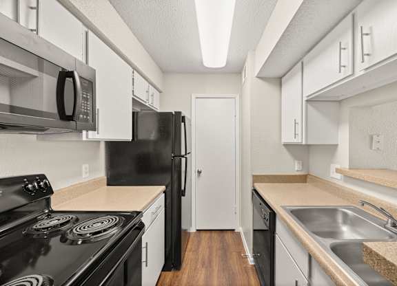 A kitchen with black appliances and white cabinets. at Montecito, Austin, TX