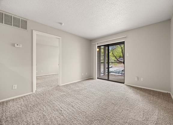 A room with a carpeted floor and a sliding glass door leading outside. at Montecito, Austin, TX, 78741