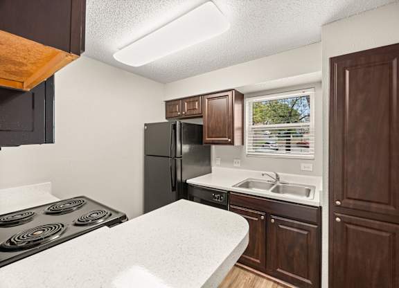 A kitchen with a black stove top oven and a black refrigerator. at Montecito, Austin, TX, 78741