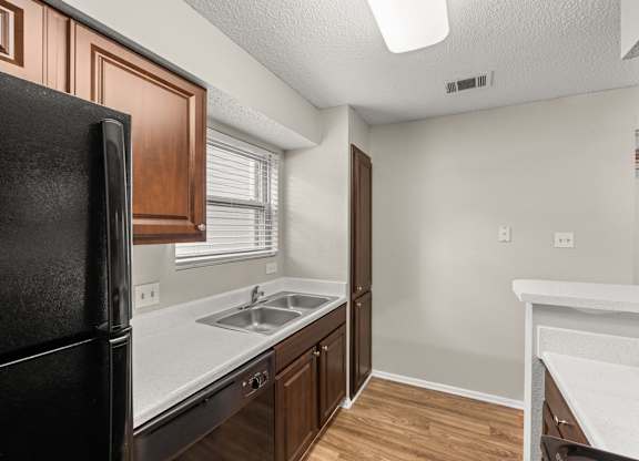 A kitchen with a black fridge and brown cabinets. at Montecito, Austin, TX, 78741