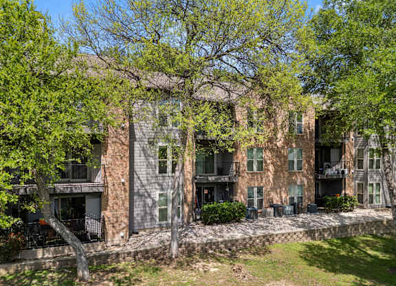 A large building with a balcony and a tree in front of it. at Montecito, Texas, 78741