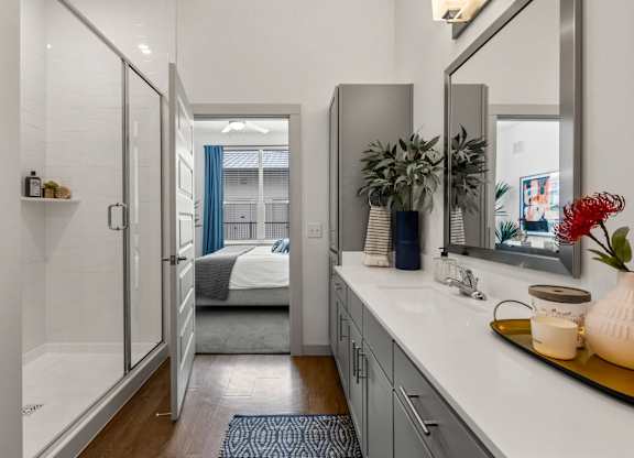 A bathroom with a walk-in shower and a double sink vanity. at The Haywood Apartments, Austin, 78748