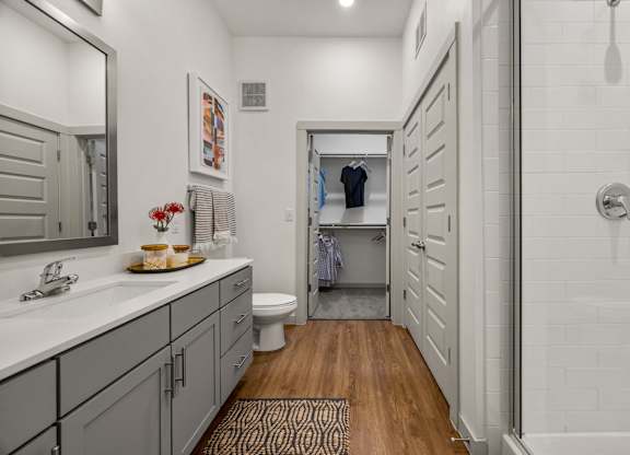 A bathroom with a toilet, sink, and a mirror. at The Haywood Apartments, Austin, Texas