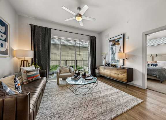 A modern living room with a brown leather couch and a glass coffee table. at The Haywood Apartments, Austin, TX, 78748