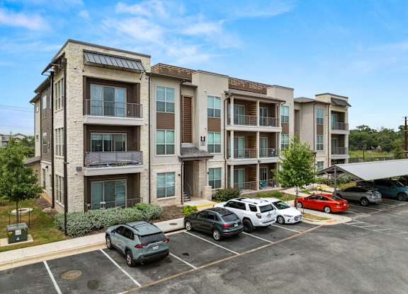 A parking lot with cars and apartment buildings in the background. at The Haywood Apartments, Austin