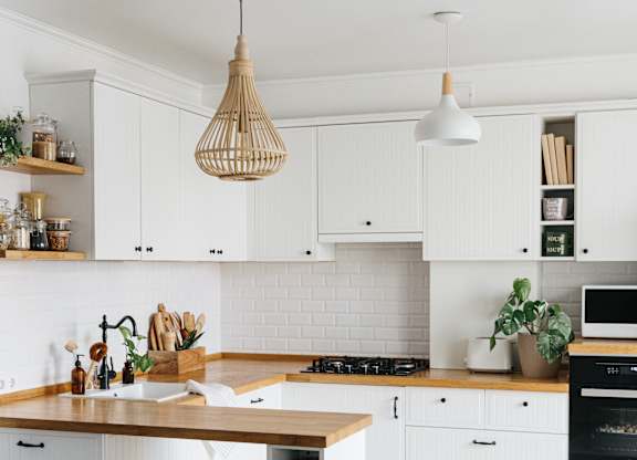 A kitchen with white cabinets and a wooden island.