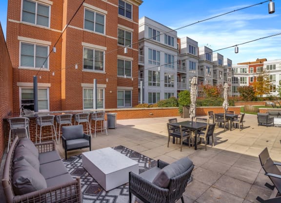 a large patio with furniture and tables in front of an apartment building