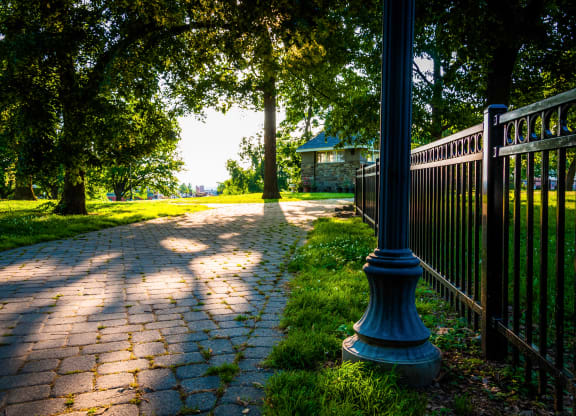 a walkway with a black fence and a house in the background