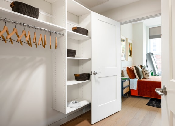 a closet with white closet doors and a white closet door with hangers