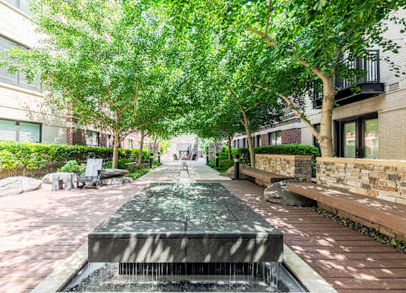 Photo of a peaceful courtyard with water features and lush greenery.