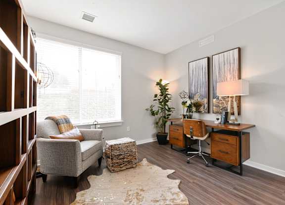 A room with a grey couch, a wooden desk, and a white wall.