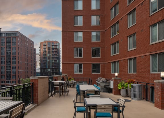 an outdoor patio with tables and chairs in front of tall buildings