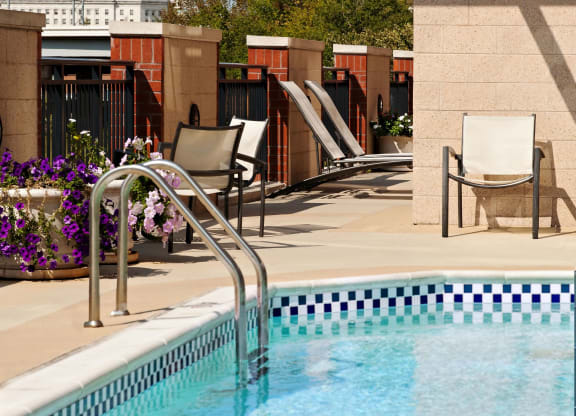 a swimming pool with chairs and a building in the background